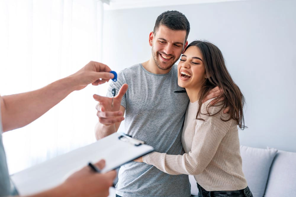 lender handing keys to a young couple