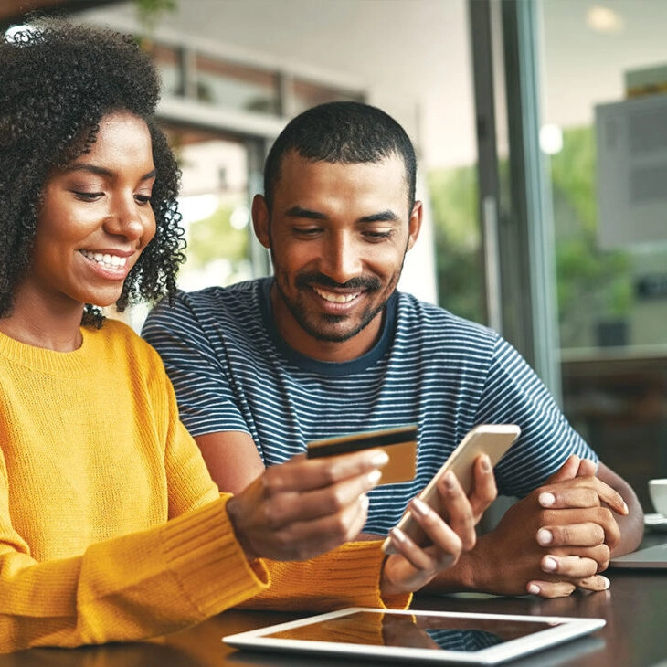 man and woman looking at smart phone and holding credit card