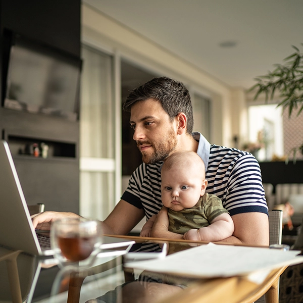 man holding his baby on his lap and looking at a laptop