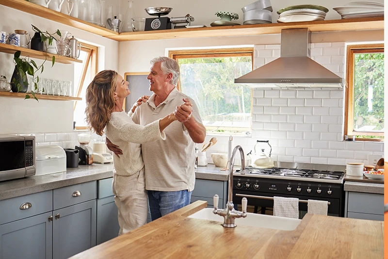 Grey haired man dancing with wife in kitchen