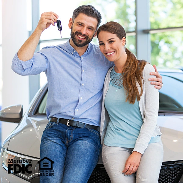 Couple at a car dealership holding the keys to their new car